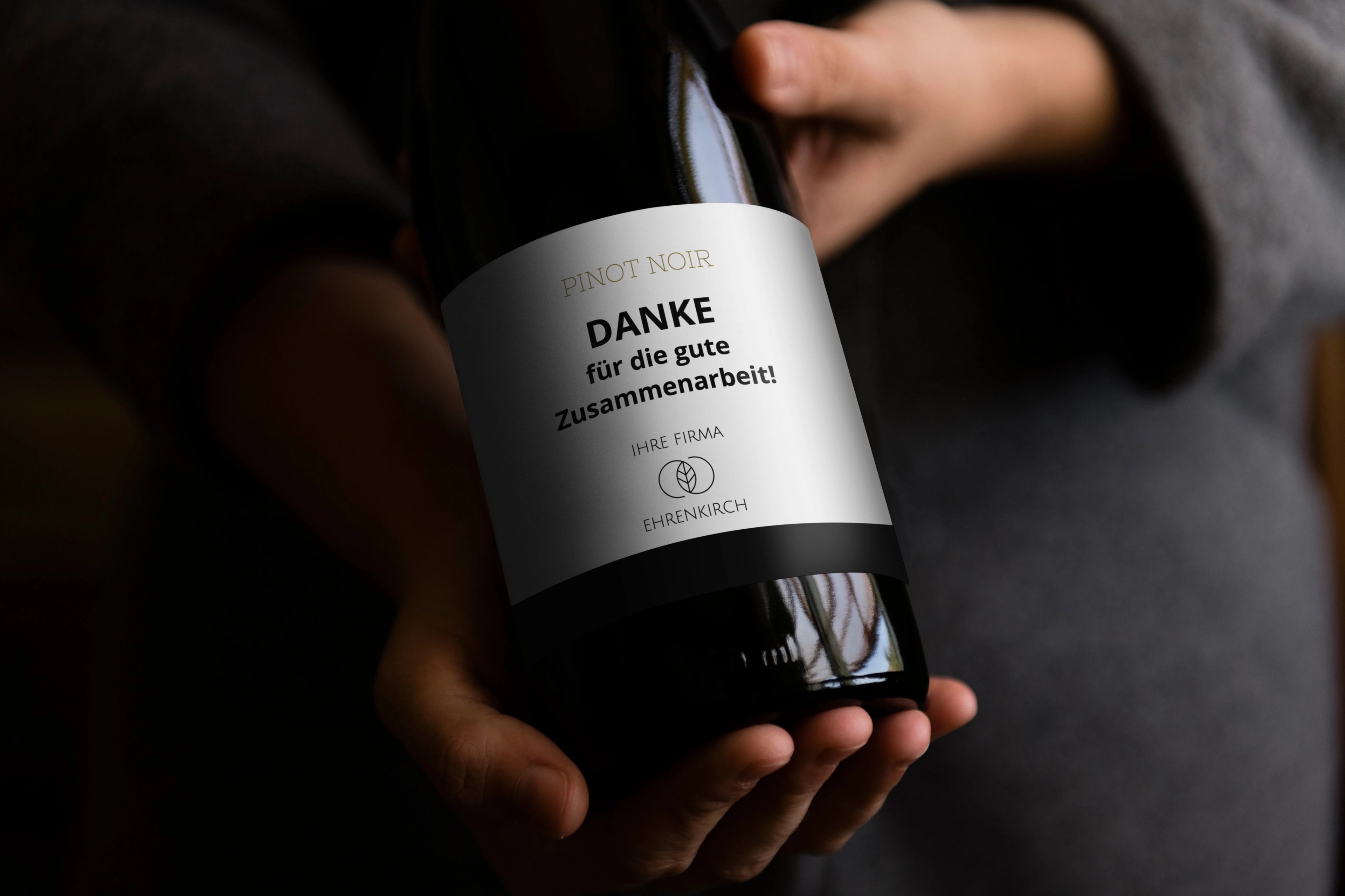 Person hält eine personalisierte Flasche mit Dankesnachricht als Geschäftsgeschenk.